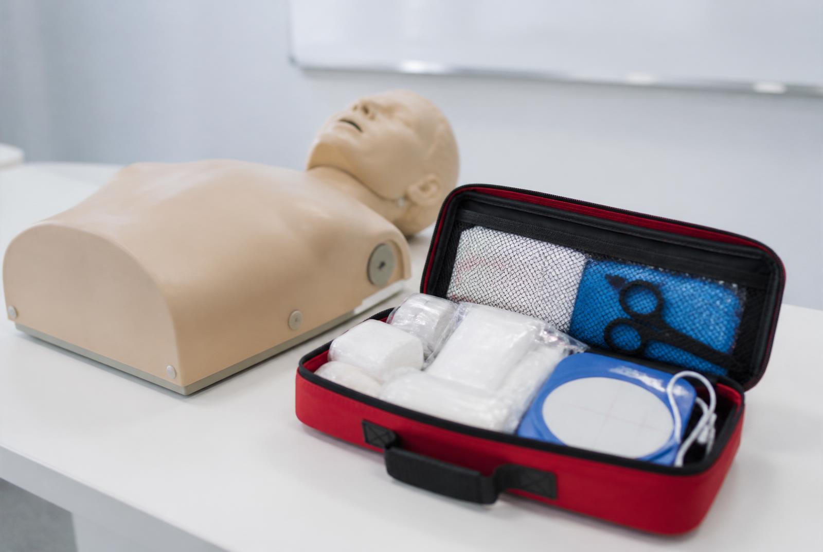 Mannequin de RCP et trousse de premiers secours sur table de formation.